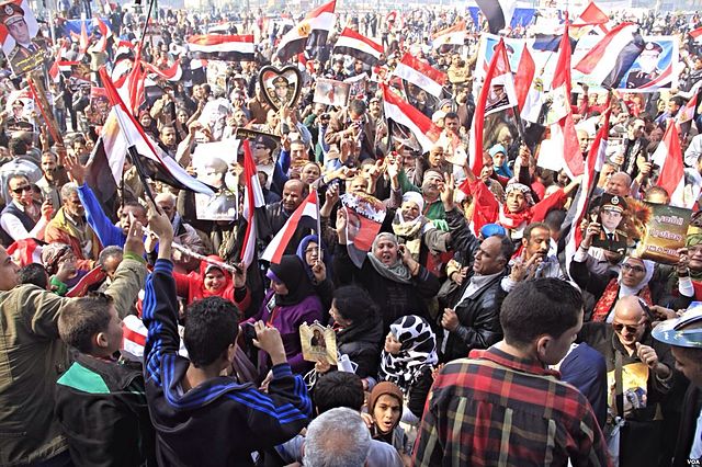 Sostenitori del nuovo presidente egiziano Abdel Fattah al Sisi festeggiano i risultati delle elezioni a piazza Tahrir, al Cairo, il 29 maggio 2014 - credito foto: „Pro-government crowds gather in Tahrir Square - Cairo - 25-Jan-2014“ von Hamada Elrasam for VOA - http://gdb.voanews.com/BDB12AEC-CF19-4A8C-A522-B7C05B884AF0_mw1228_mh548_s.jpg. Lizenziert unter Gemeinfrei über Wikimedia Commons.