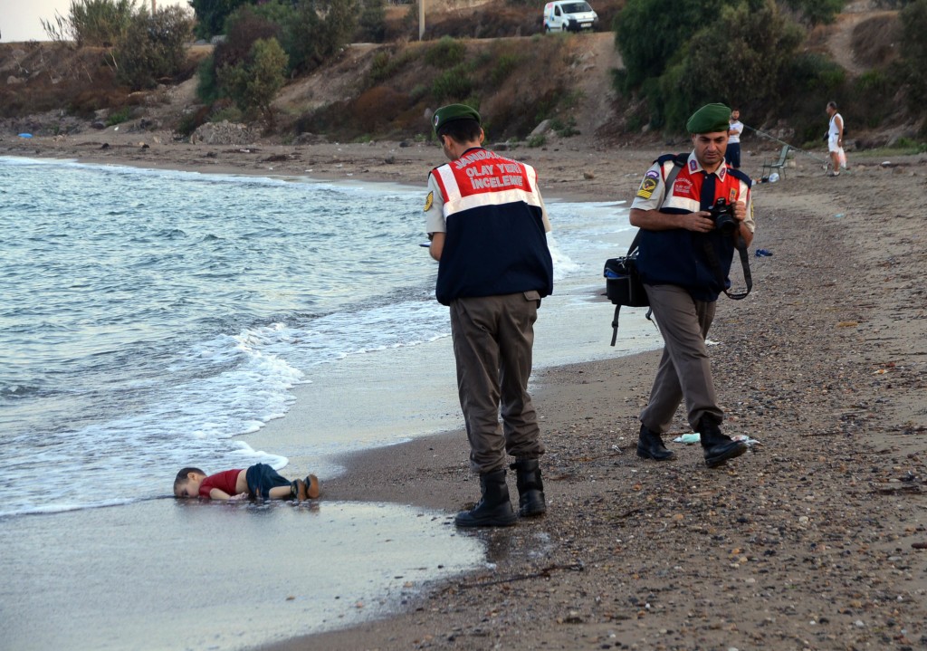 RETRANSMISSION TO REMOVE REFERENCE OF BID TO MOVE TO CANADA -Paramilitary police officers investigate the scene before carrying the lifeless body of Aylan Kurdi, 3, after a number of migrants died and a smaller number were reported missing after boats carrying them to the Greek island of Kos capsized, near the Turkish resort of Bodrum early Wednesday, Sept. 2, 2015.  The tides also washed up the bodies of Rehan and Galip on Turkey's Bodrum peninsula Wednesday, Abdullah survived the tragedy. (ANSA/AP Photo/DHA) TURKEY OUT  ONLINE OUT